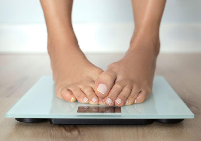 Füße auf Wage mit verschränkten großen Zehen