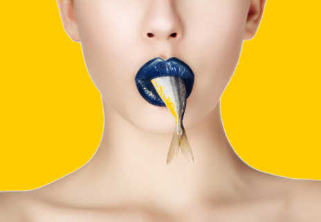 Frau mit Fisch im Mund auf gelbem Hintergrund