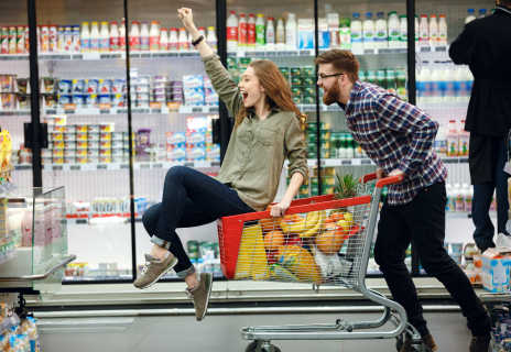 Junges Paar im Supermarkt - die Frau sitzt im Einkaufswagen