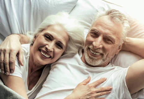 Älteres Paar liegt zusammen strahlend im Bett