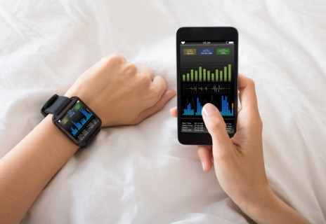 Mann überprüft Daten seiner Smartwatch mit dem Handy